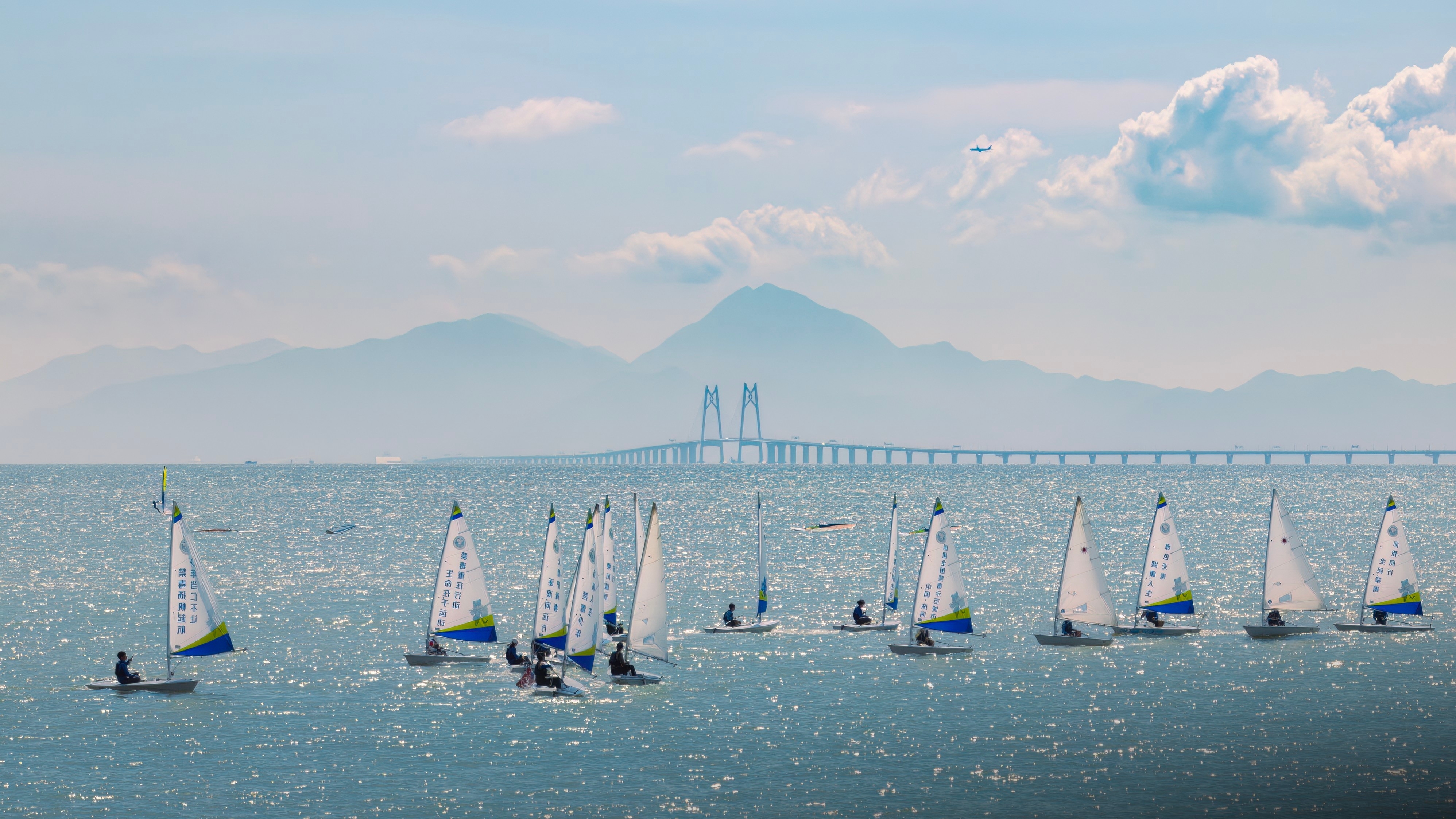 帆影映碧波，远方港珠澳大桥如巨龙卧波，山脉轮廓清晰，景致交融成画。南方+拍客 卓文麟 摄